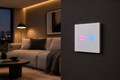 White 2-gang smart WiFi wall switch with glowing touch buttons on a dark wall in a minimalist living room